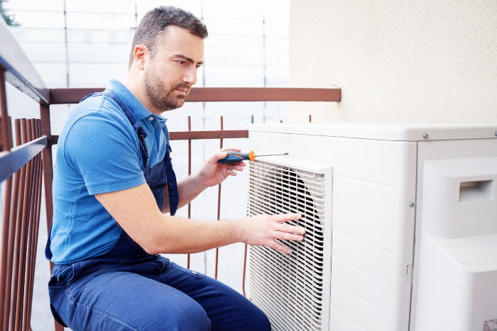 Technician in blue overalls fixing an AC, showcasing HVAC expertise in Chicago & suburbs